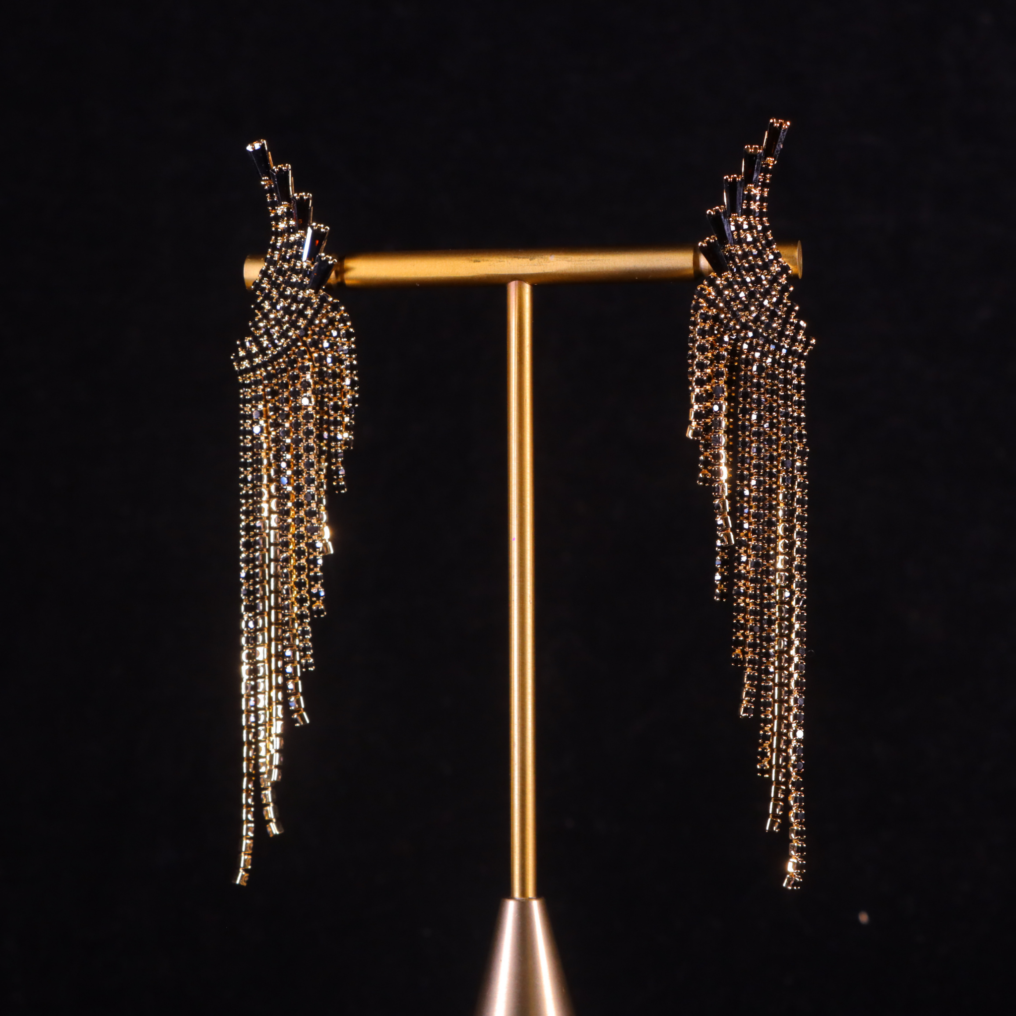 A pair of gilded gold and black party earrings with a tassel design