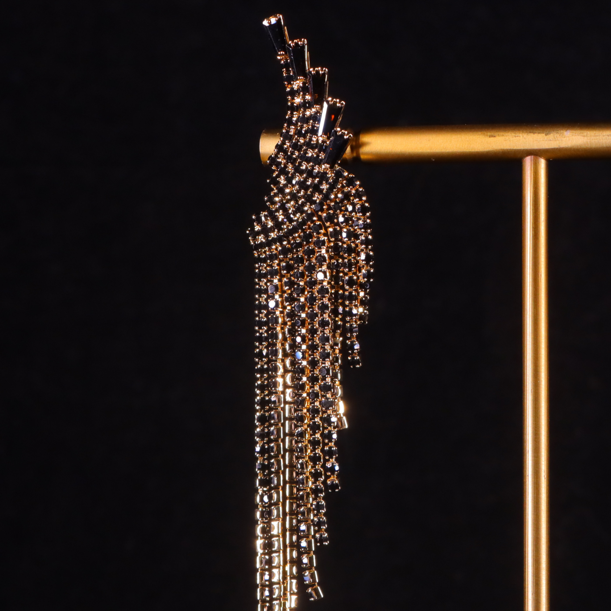 A pair of gilded gold and black cocktail party earrings with a tassel design