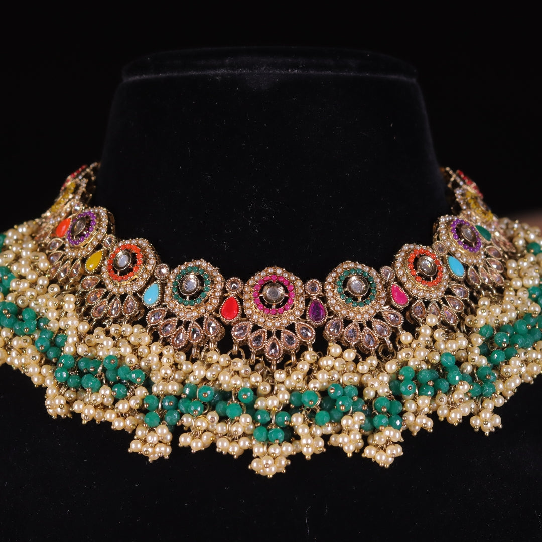 A traditional Indian kaleidoscope necklace featuring a gold-colored metal base with multicolored stone embellishments and pearl-like beads